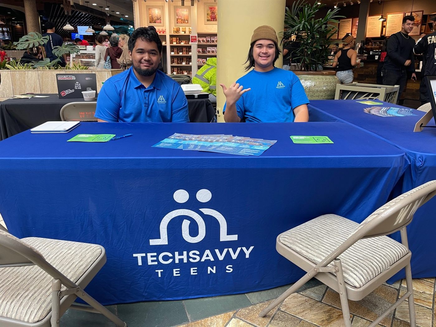 Two Tech Savvy Teens volunteers staffing an outreach table with program flyers