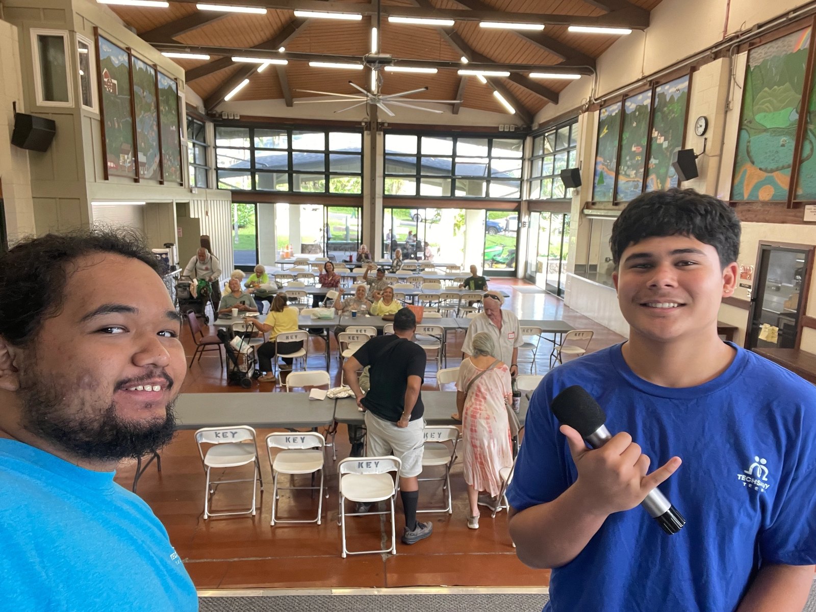 Two Tech Savvy Teens volunteers with a microphone at a community centre gathering