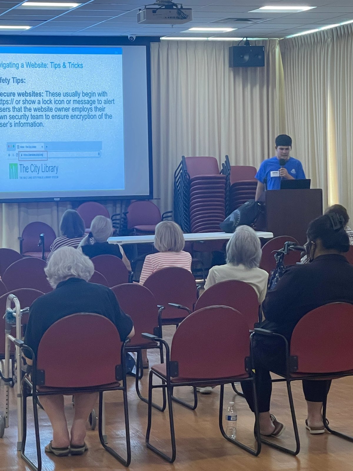 A Tech Savvy Teen presenting an internet-safety slide to a room of seated kūpuna