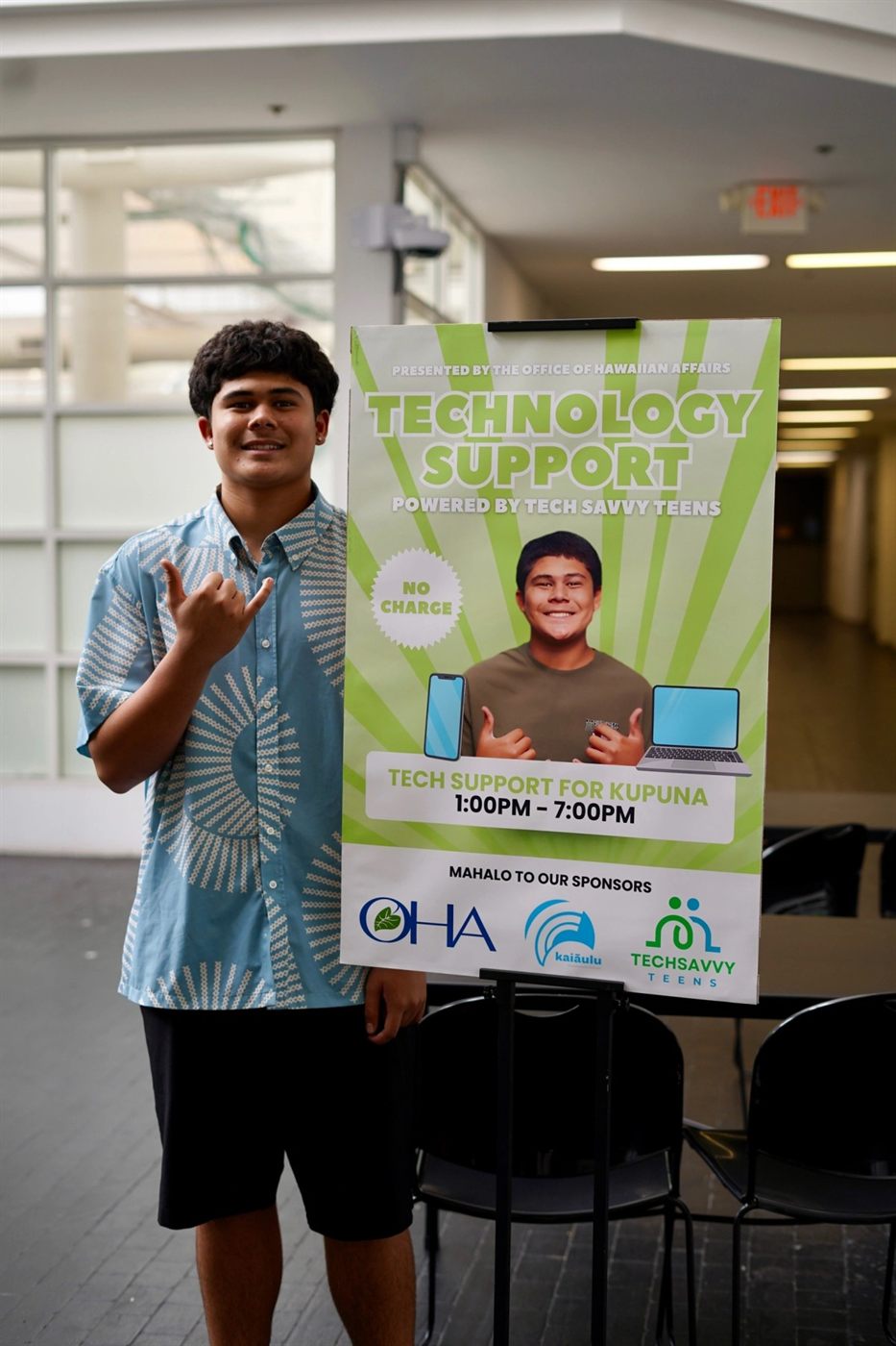 Co-founder Jaffer Dakroub throwing shaka beside a Technology Support poster presented by the Office of Hawaiian Affairs